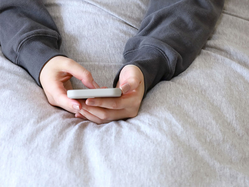 ベッドでスマホを操作する写真